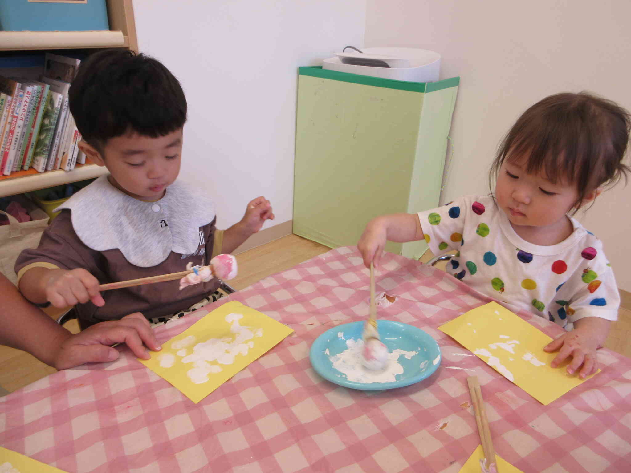 丁寧にまんべんなく塗っているTくんと絵の具皿の中の絵の具に興味津々のRちゃん。